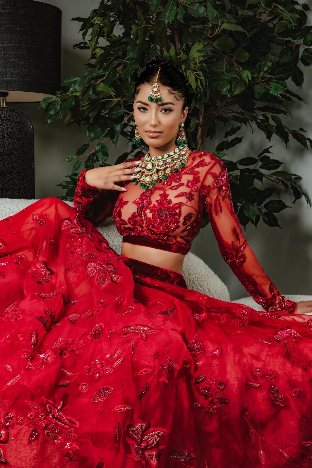 Bride in red lehenga with emerald kundan jewellery set with greenery